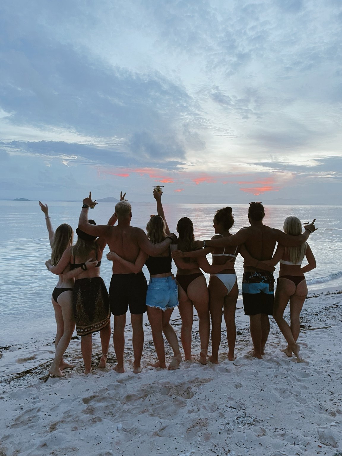 A group of friends standing together at sunset on the beach