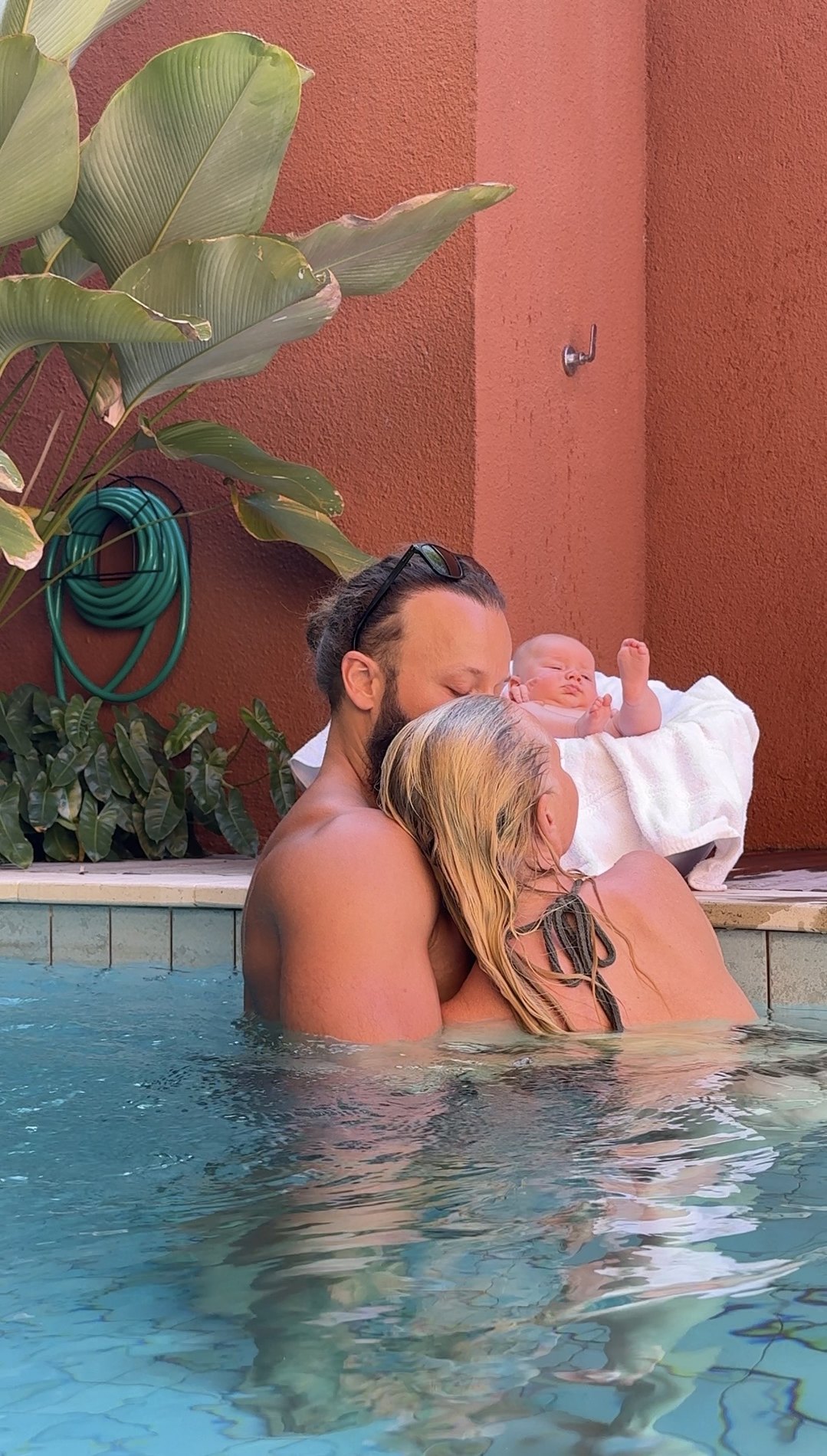 A family holding their baby in a tropical pool